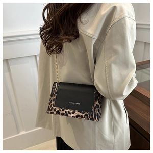 Detail of stylish leopard print shoulder bag with gold chain strap on female model