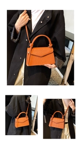 Detail of orange woven textured crossbody bag with knotted handle and envelope flap