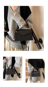 Detail of black woven shoulder bag featuring a knotted handle and gold metal rings