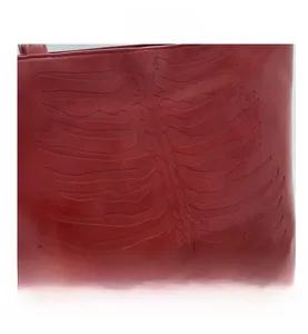 Close-up of dark red leather tote bag featuring unique 3D rib cage embossed design details