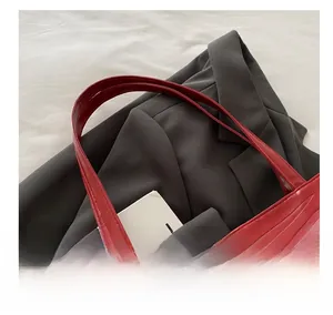 Close-up of red leather tote bag featuring detailed embossed floral patterns and sturdy handle