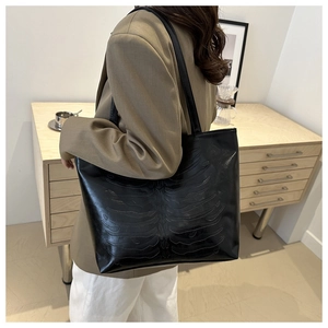 Close-up of black leather tote bag featuring unique 3D ribcage texture and long straps