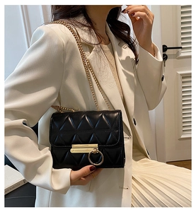 Detail of black quilted leather crossbody bag with gold chain and metal ring buckle