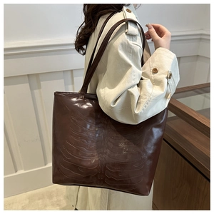 Detail of a deep brown faux leather tote bag with unique ribbed bone embossed pattern