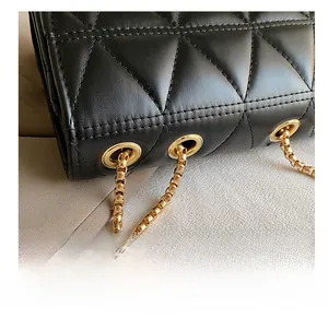 Close-up of black quilted leather with gold chain strap and metallic eyelet details