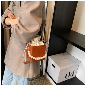 Detailed view of floral embossed brown box bag with pearl handle and golden chain strap