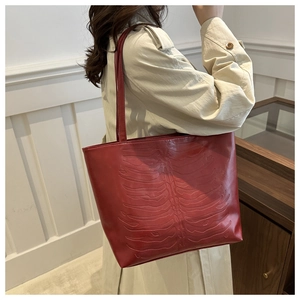 Detail of red tote bag featuring unique ribcage embossed pattern and long shoulder straps