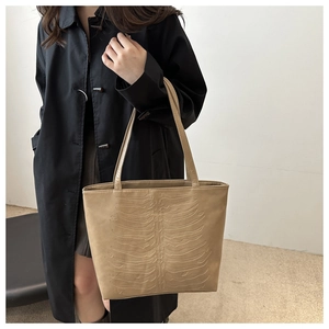 Detailed view of beige tote bag featuring unique 3D rib-embossed texture on PU leather