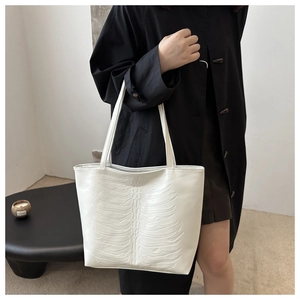 White faux leather tote bag with unique embossed skeleton design shown on model shoulder