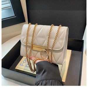Close-up of off-white quilted crossbody bag with gold chain and circular metal buckle