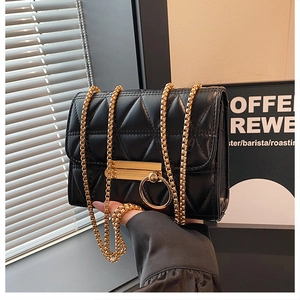 Detail of black quilted crossbody bag with gold chain strap and ring hardware