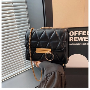 Close-up of black quilted crossbody bag with gold ring buckle and chain strap detail