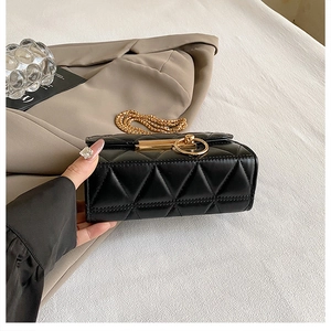 Close-up of black quilted mini bag with gold circular metal buckle and chain strap