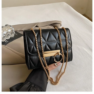 Detailed view of black quilted mini bag with gold chain strap and ring lock closure