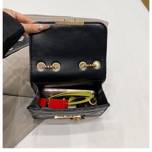Close-up showing internal storage of black quilted chain bag with phone and sunglasses