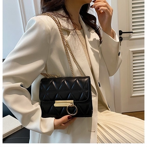 Detail of black quilted leather crossbody bag with golden ring buckle and chain strap