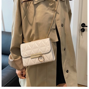 Close-up of a cream quilted crossbody bag featuring a golden ring clasp and chain strap