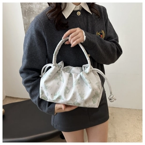 Detalle del estampado de mariposas y diseño plisado en bolso de mano blanco