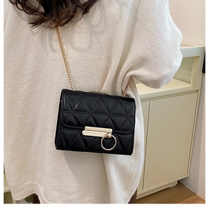 Detail of black quilted crossbody bag with gold chain strap and metal lock closure