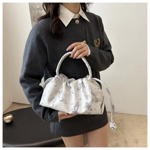 Detalle de bolso de mano tipo nube blanco con estampado de mariposa y fruncido