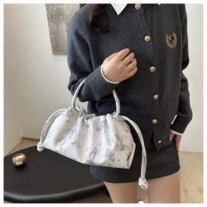 Detalle de bolso fruncido blanco con estampado de mariposas grises y asa redonda