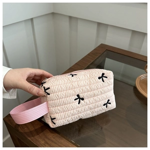 Close-up of pink quilted handbag with delicate black bow embroidery and ribbon handle