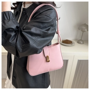 Pink minimalist underarm bag with gold metal clasp on model in lifestyle setting