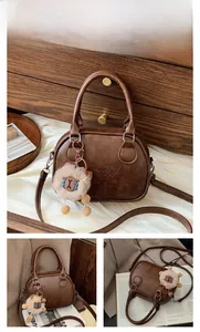 Detail view of brown vintage bowling bag with LUCKY WHO embossing and sheep plush charm