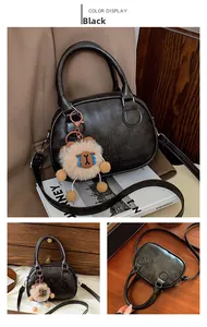 Detail of black matte leather bowling bag with embossed letters and plush sheep charm