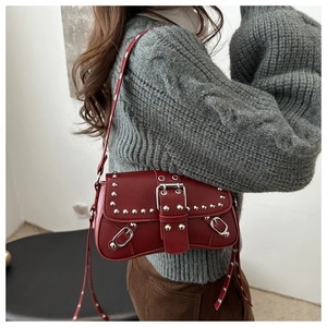 Detail of burgundy leather shoulder bag featuring silver rivets and metal buckle strap