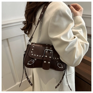 Detail view of brown leather crossbody bag with silver studs and adjustable strap