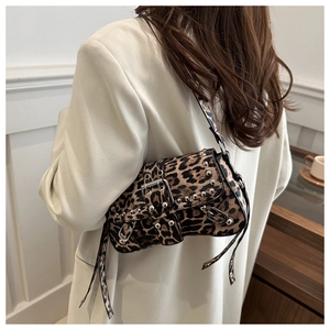 Y2K style leopard print shoulder bag with silver metal studs worn by a model in a white blazer