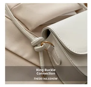 Close-up of golden buckle link and knotted strap detail on white leather crossbody bag