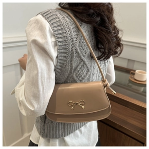 Detail of a chic beige shoulder bag with an elegant golden bow buckle on smooth leather