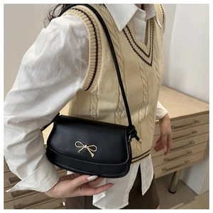 Close-up of black matte faux leather bag with a stylish golden bow metal buckle detail