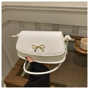 Detail of white mini square bag with golden bow clasp and smooth leather texture