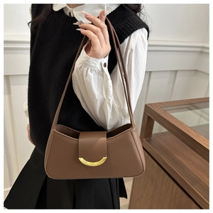 Close-up of vintage brown leather underarm bag with gold crescent buckle detail