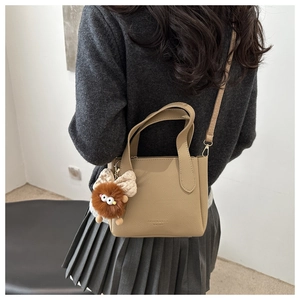 Detail of khaki leather bucket bag with ring handles and plush monster charm