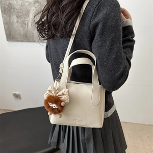 Minimalist white lychee texture bucket bag with plush charm and plaid bow accessory