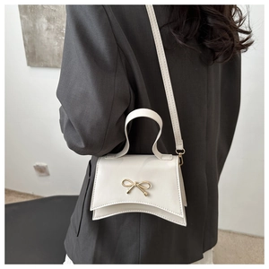 Vue détaillée d'un sac bandoulière en cuir blanc avec nœud porté par un mannequin
