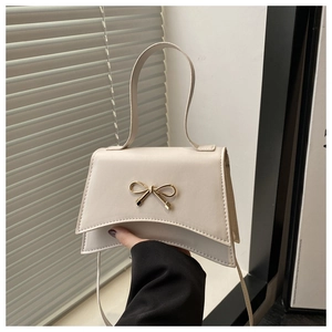Détail du sac bandoulière crème avec fermoir nœud doré et poignée en similicuir