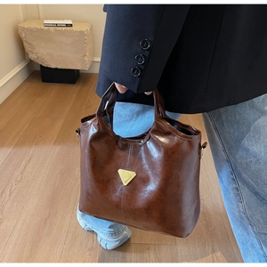 Detail of dark brown leather tote bag with vintage texture and golden triangle logo