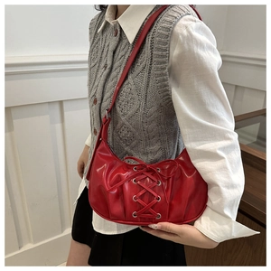 Detail of red crescent shoulder bag with corset-style lace-up bow and silver eyelets