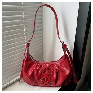 Close-up of red pleated underarm bag featuring ballet style ribbon bow and sleek finish