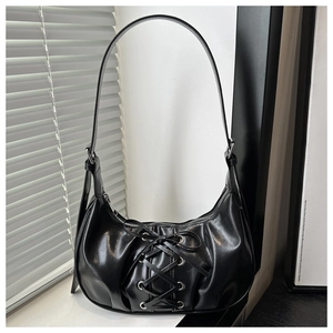 Detail of corset-style lace-up straps and metal eyelets on a black PU leather bag
