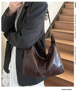 Detail of a large chocolate brown Hobo shoulder bag with chain strap on a model