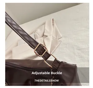 Close-up of adjustable golden metal buckle on dark brown leather shoulder bag strap