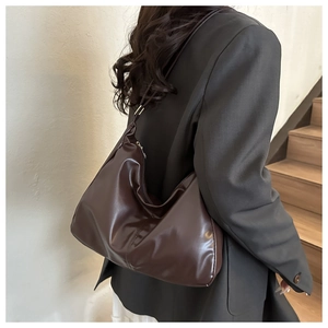 Detail of dark brown glossy PU leather shoulder bag with smooth zipper closure texture