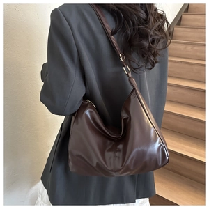 Side view of large dark brown hobo bag with glossy finish and gold metal hardware