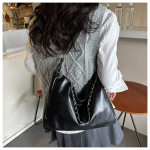 Detail of a large black leather hobo bag featuring stylish metal chain shoulder strap
